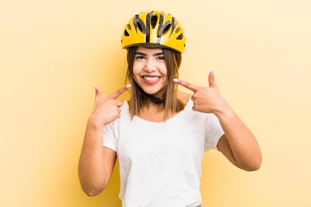 Vrij Spaans meisje dat vol vertrouwen glimlacht en wijst naar haar eigen brede glimlachfietsconcept