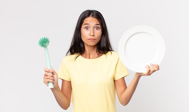 Vrij spaanse vrouw die een epty schone schotel houdt