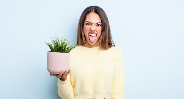 Vrij Spaanse vrouw met vrolijke en rebelse houding, grappen maken en tong uitsteken. kamerplant concept