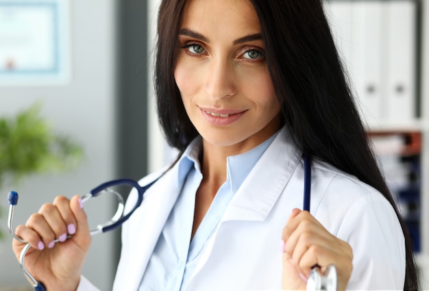 Vrij volwassen Kaukasische vrouwelijke GP uitrekkende stethoscoop in handen
