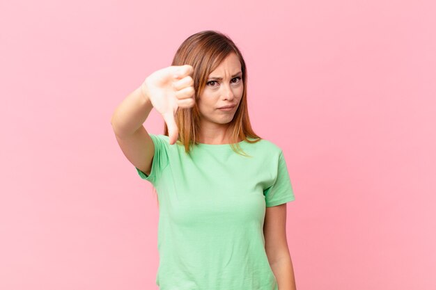 Vrij volwassen vrouw die zich boos voelt en duimen naar beneden laat zien