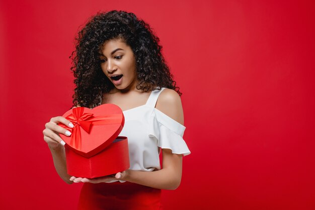 Vrij vrolijke zwarte het openen hart gevormde valentijnskaartgift die op rood wordt geïsoleerd