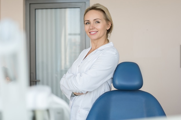 Vrij vrouwelijke tandarts poseren in de kliniek