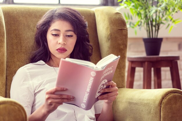 Vrije dag. Mooie knappe vrouw die een boek leest terwijl u thuis ontspant