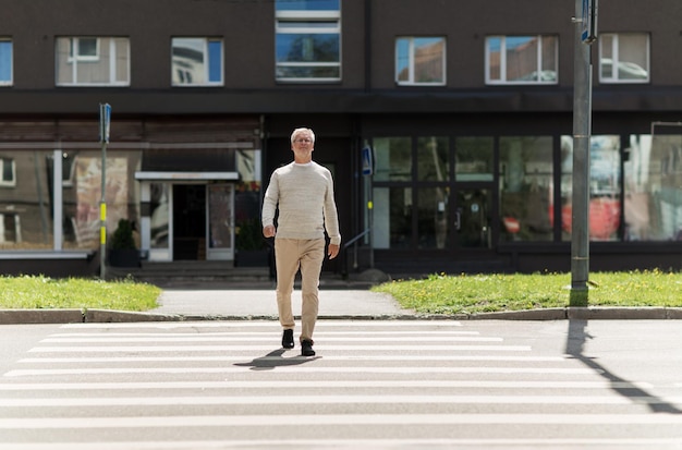 vrije tijd en mensen concept - senior man lopen langs zomer stad zebrapad