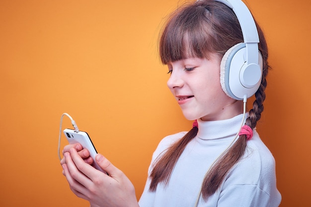 Vrije tijd en vermaak, Kaukasisch tienermeisje dat aan muziek met hoofdtelefoons luistert die de telefoon op gekleurd gebruiken