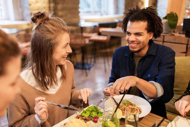 vrije tijd, eten, drinken, mensen en vakantie concept - gelukkige vrienden eten en drinken in restaurant