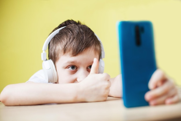Vrije tijd kinderen technologie en mensen concept lachende jongen met smartphone en koptelefoon