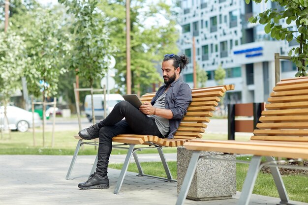 vrije tijd, technologie, communicatie, reizen en mensen concept - man met tablet pc computer zittend op straat bankje in de stad
