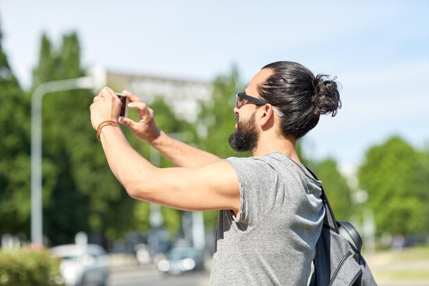 vrije tijd, technologie en mensenconcept - hipster man die foto's of video's maakt met een smartphone op straat