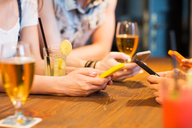 vrije tijd, technologie, levensstijl en mensenconcept - close-up van handen met smartphones aan de bar