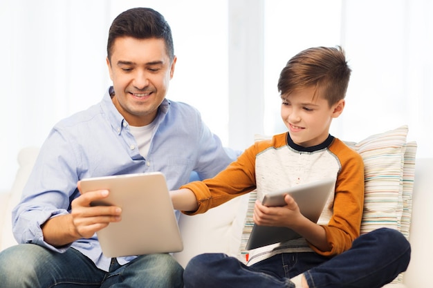 vrije tijd, technologie, technologie, familie en mensenconcept - gelukkige vader en zoon met tablet pc-computernetwerken of thuis spelen