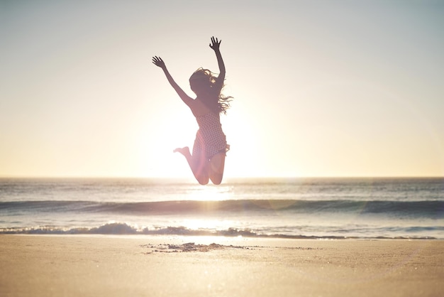 Vrijheid ligt in brutaal zijn Shot van een jonge vrouw die midden in de lucht springt op het strand