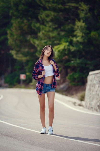 Vrijheid reizen concept zomer weekend hipster meisje reislust wandelen op asfaltweg in wilde landen Mooi jong meisje met het uiterlijk van Zuid-Azië