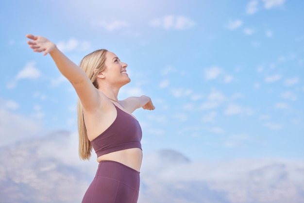 Vrijheidsarmen en vrouw op blauwe luchtmodel voor fitness, gezondheid, buitenoefening en spirituele wellness Winnaar en gelukkige persoon of atleet met sportsucces, stressvrij en handen in de lucht