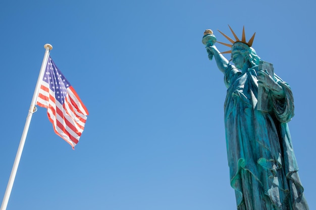 Foto vrijheidsbeeld met amerikaanse vlag drijvend in mat met wind op blauwe hemel