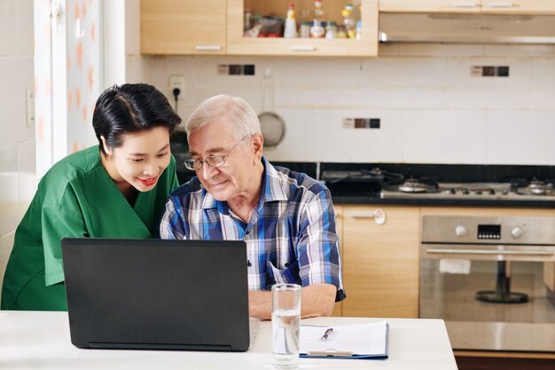 Vrijwilliger die hogere mens toont hoe laptop te gebruiken