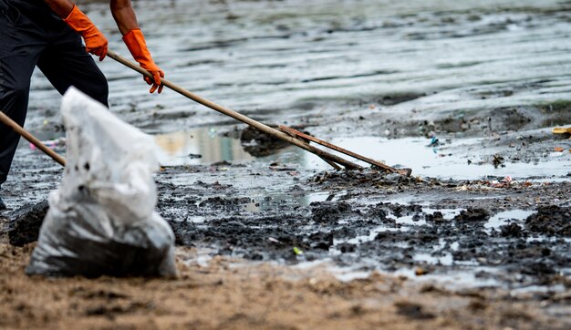 Vrijwilligers gebruiken de rake om het afval uit de zee te vegen. Strandreiniger die afval verzamelt