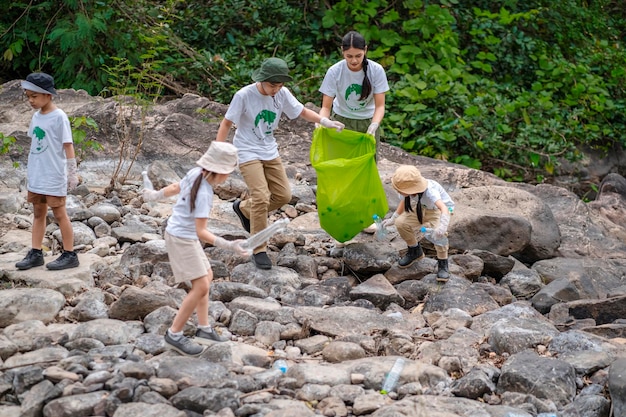 Foto vrijwilligers uit azië en kinderen verzamelen plastic flessen die door de stroom in vuilniszakken stromen