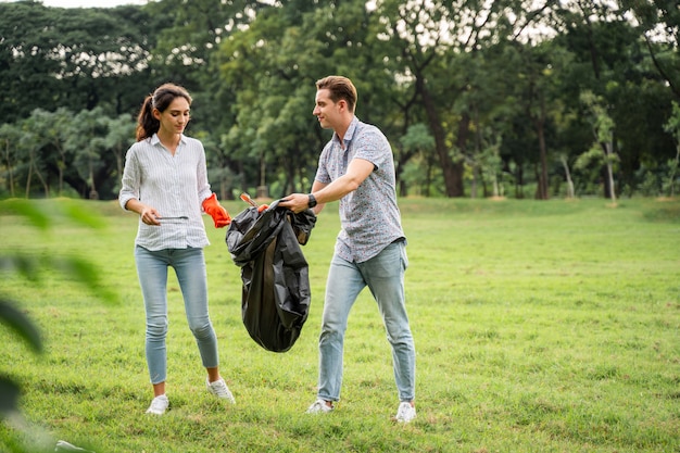 Vrijwilligersliefhebbers koppelen handschoenen aan om afval op te halen in het park Om het milieu schoon te houden