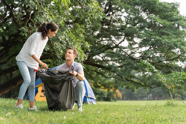 Vrijwilligerspaar dat handschoenen draagt lopend om afval in het park op te halen Om het milieu schoon te houden