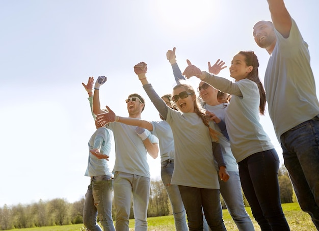 vrijwilligerswerk, liefdadigheid en mensenconcept - groep gelukkige vrijwilligers die succes vieren in het park