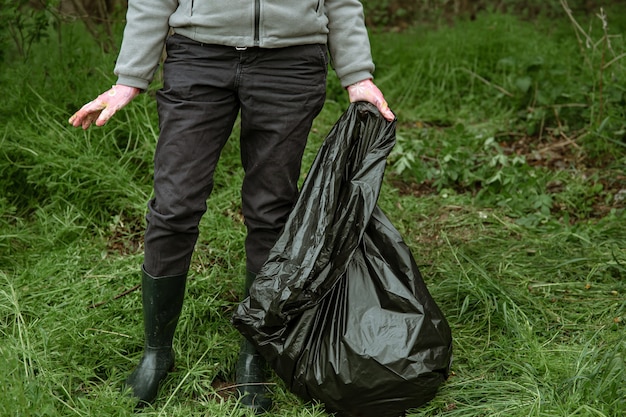 Vrijwilligerswerk met een vuilniszak op reis naar de natuur, het milieu schoonmaken.