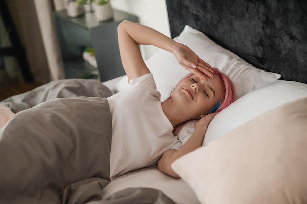 Vroeg in de ochtend Jong meisje met roze haar in bed dat er slaperig uitziet