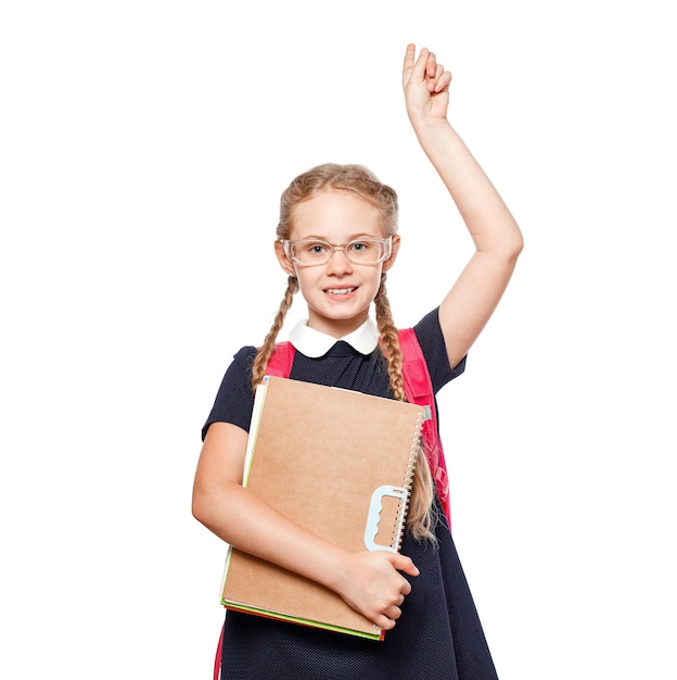 Vrolijk 8 jaar oud schoolmeisje met rugzak die uniforme staande draagt, geïsoleerd op een witte achtergrond. Klaar voor school.