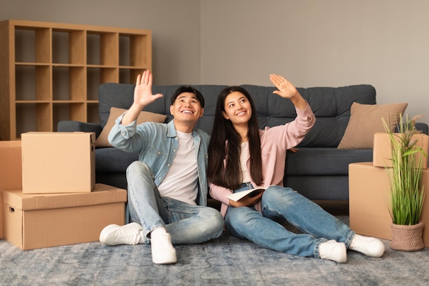 Vrolijk Aziatisch koppel plant renovatie in nieuw appartement na verhuizing