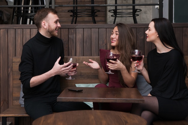 Vrolijk bedrijfsgesprek in bar. Gelukkig lachende mensen samen, na het werk ontspanning. Aangename communicatie met rode wijn, vriendschapsconcept