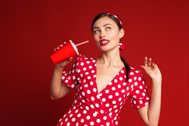 Vrolijk donkerbruin pin-up meisje dat frisdrank houdt