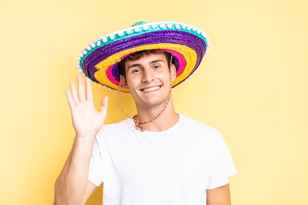 Vrolijk en vrolijk glimlachen, met de hand zwaaien, je verwelkomen en begroeten, of afscheid nemen. mexicaanse hoed concept