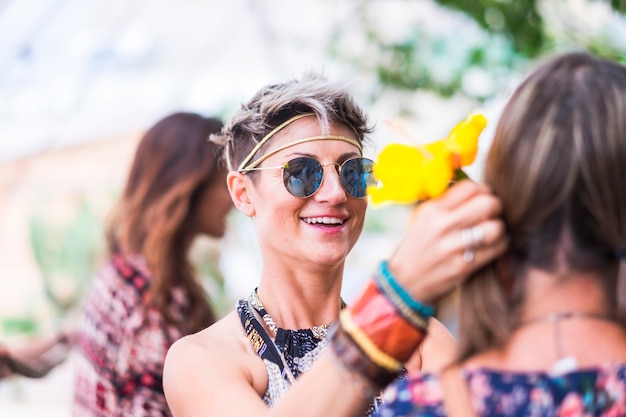 Foto vrolijk gekleurde hippie-stijl gratis en lachende jonge blonde alternatieve vrouw met vrienden samen veel plezier buiten