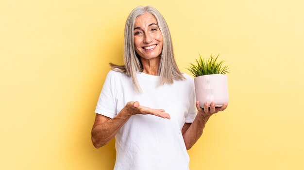 Vrolijk glimlachen, je gelukkig voelen en een concept in kopieerruimte tonen met een handpalm die een decoratieve plant vasthoudt