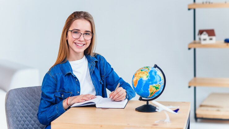 Vrolijk hipstermeisje die als journalist werken die van vrije tijd in cafetaria genieten en camera tijdens onderbreking bekijken, succesvolle gelukkige schrijver die nieuwe nieuwe ideeën creëren terwijl het zitten aan coworkingruimte