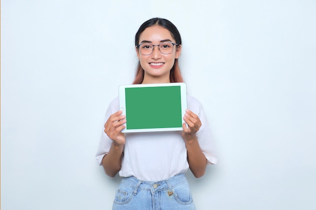 Vrolijk jong Aziatisch meisje in witte t-shirt met digitale tablet met leeg scherm geïsoleerd op een witte achtergrond