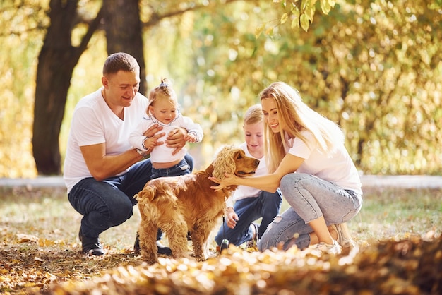 Vrolijk jong gezin met hond rust samen in een herfstpark.