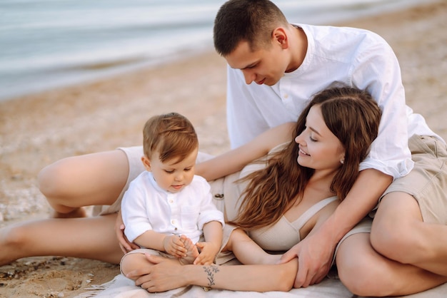 Vrolijk jong gezin met kleine babyjongen die samen tijd doorbrengt op het strand