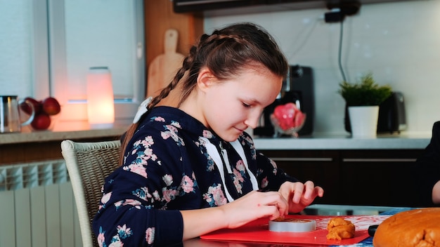 Vrolijk jong meisje dat ovenschaal vult met het concept van familietradities van gebakdeeg