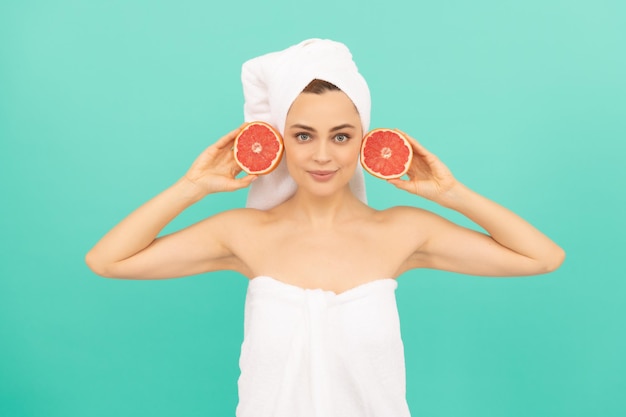 Vrolijk jong meisje in handdoek na douche met grapefruit op blauwe achtergrond