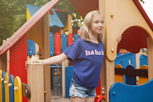 Vrolijk jong meisje met plezier op de speelplaats van het park