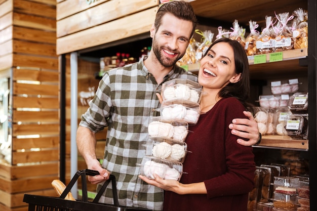 Vrolijk jong stel doet boodschappen en koopt marshmalows in de supermarkt