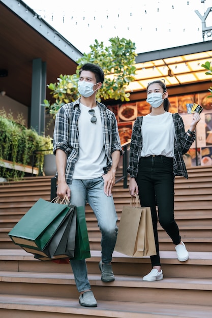 Vrolijk jong stel in masker met meerdere papieren boodschappentas