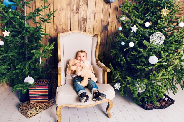 Vrolijk jongetje spelen met zijn speelgoed door de kerstboom