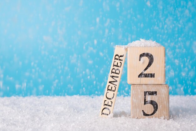 Vrolijk kerstconcept. Foto van ornamentsamenstelling van houten kalender met 25 december en vallende sneeuw