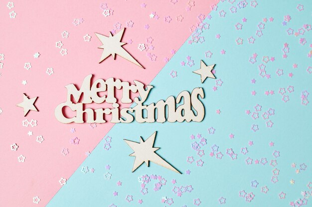 Vrolijk kerstfeest en nieuwjaarssterren belettering op roze en blauwe achtergrond met kerstglitter