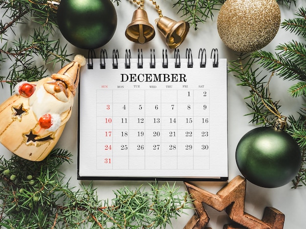 Vrolijk Kerstfeest Gelukkige Nieuwjaar Kalender en kerstversieringen liggen op een lege tafel Closeup uitzicht van bovenaf Gefeliciteerd voor geliefden familieleden vrienden collega's