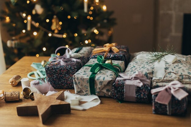 Vrolijk kerstfeest Kerstcadeau inpakken Stijlvol kerstcadeau feestelijk inpakpapier linten schaar vintage ornamenten en koperen bellen op houten tafel Voorbereiding wintervakantie