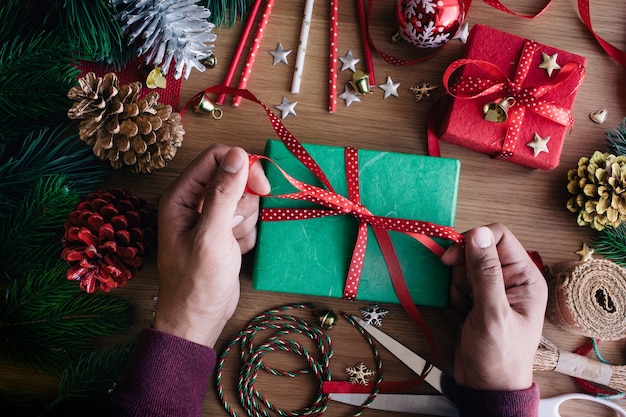 Vrolijk kerstfeest plat lag met menselijke hand versieren geschenkdoos aanwezig